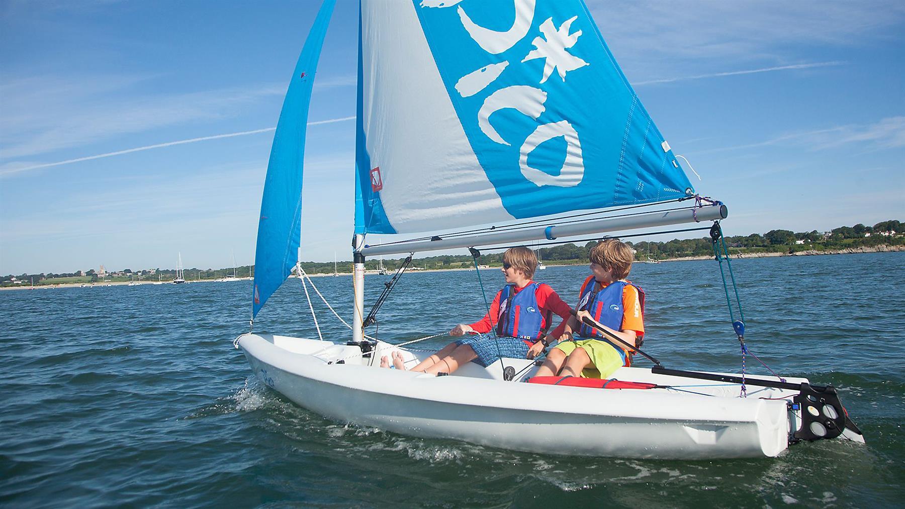 Laser Pico sailing on calm waters with two young boys.